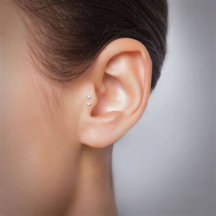 Tragus piercing with a stud earring (L) and in a love shaped earing (R)